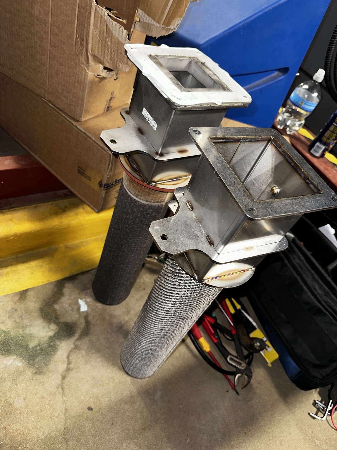 Two cylindrical commercial boiler burner assemblies removed from the appliances