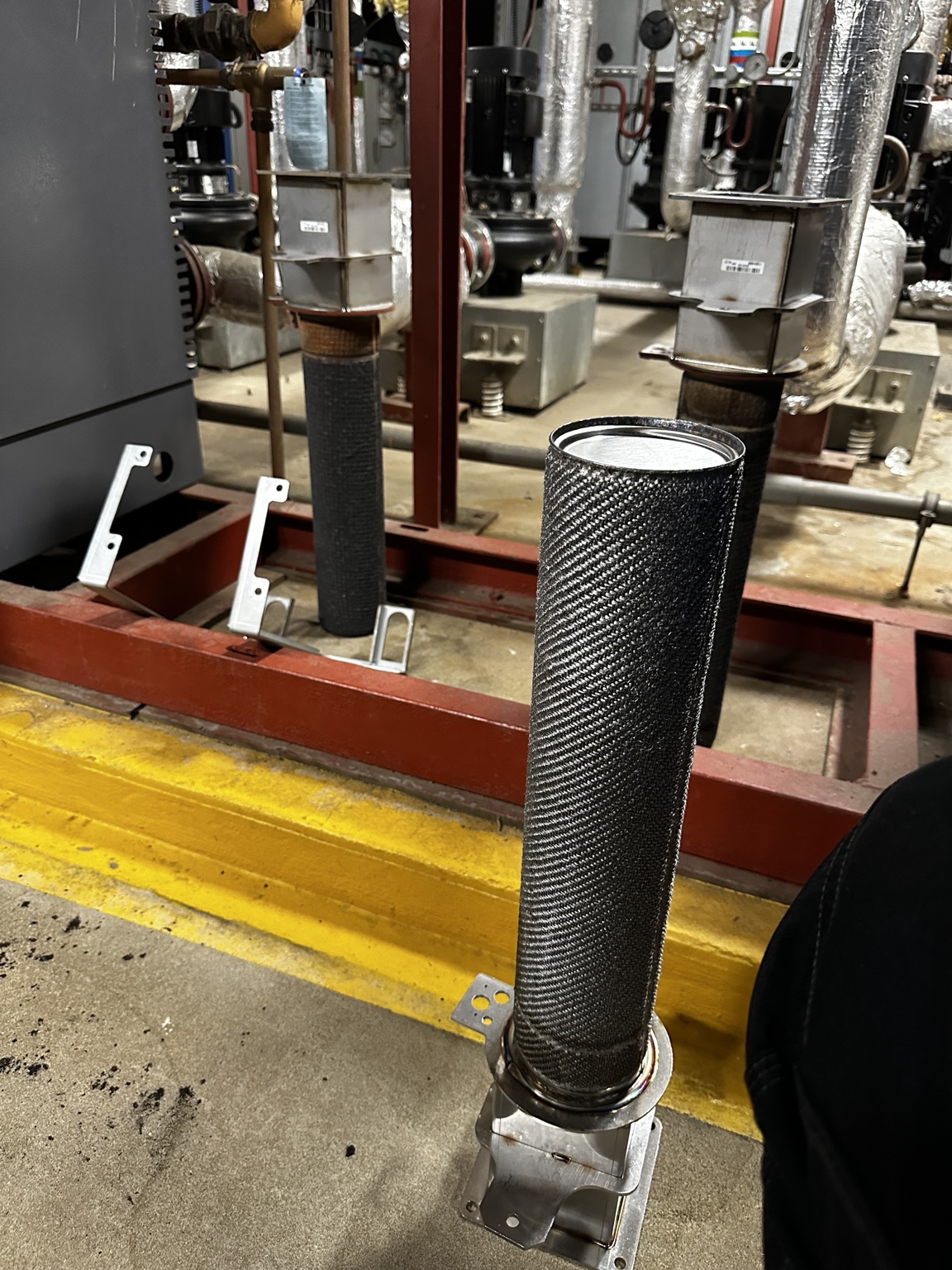 Cylindrical burner assembly alongside commercial boiler plant